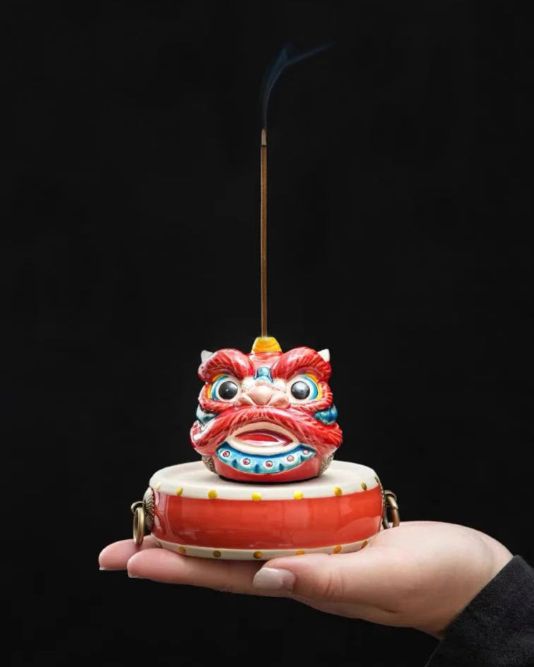 Colorful awaken lion incense holder held in a hand against a black background