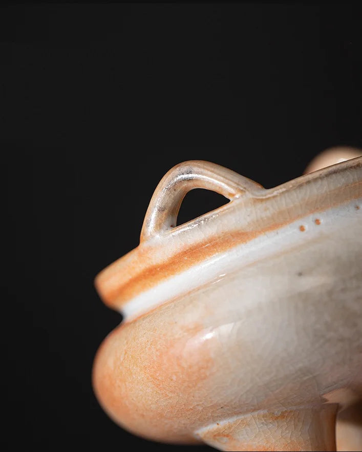 Close-up of a ceramic tripod incense burner on a black background