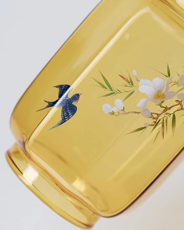 the candle holder's top is the amber glass jar with swallows frolic among blooming flowers