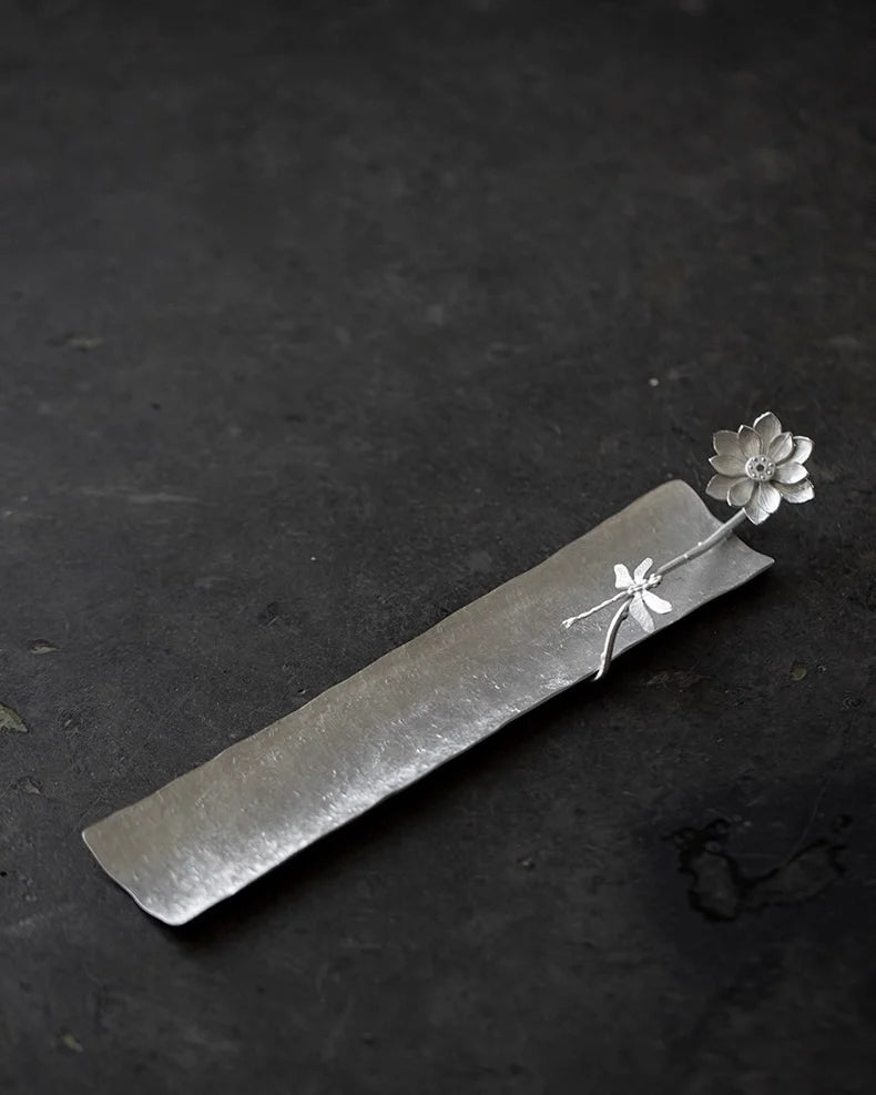 Silver incense holder with floral design on a dark background