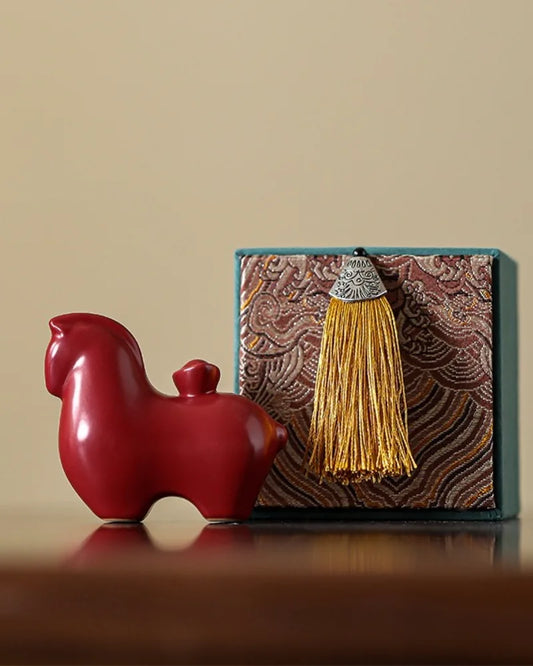 Chinese Tang horse figurine displayed beside a brocade gift box with silk tassel