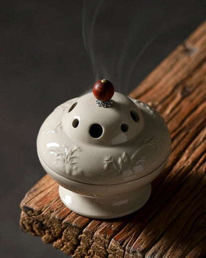 The smoke accompanied the gray and white ceramic incense burner, reflecting a calm and elegant atmosphere, suitable for feng shui ritual.
