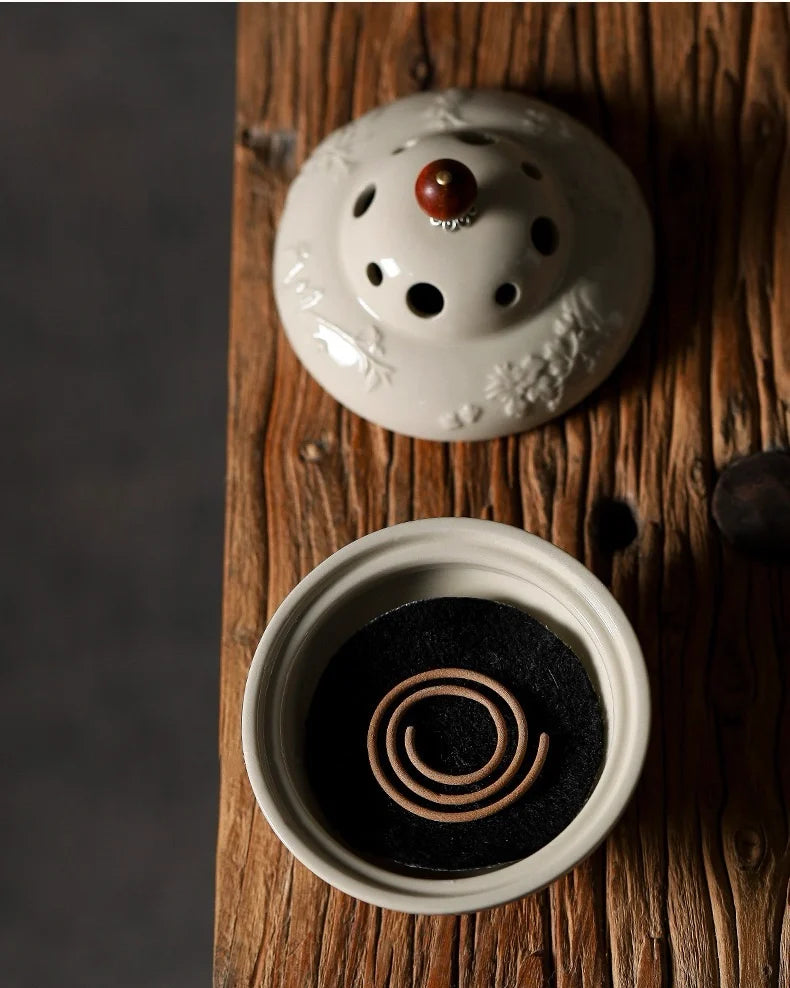 Incense burner is with coiled incense on a wooden surface, The lid is adorned with a polished red agate, a stone long cherished for its warmth and protective aura.