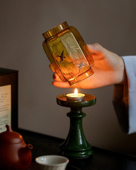 a lit candle inside an amber glass jar and emerald green base show our bifang studio's fengshui decor
