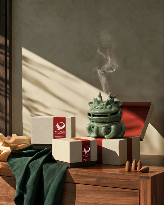 Celadon dragon incense burner with two boxes of backflow incense cones on a wooden cabinet