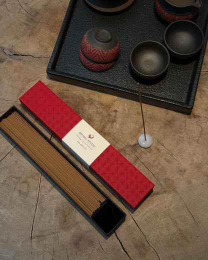 Classical Chinese handmade incense sticks in red packaging beside traditional Chinese tea ware.