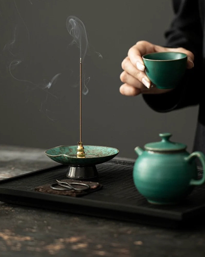Burning incense on a blue-green ceramic incense stick holder with reactive glaze finish, perfect for Chinese incense ritual and meditation spaces