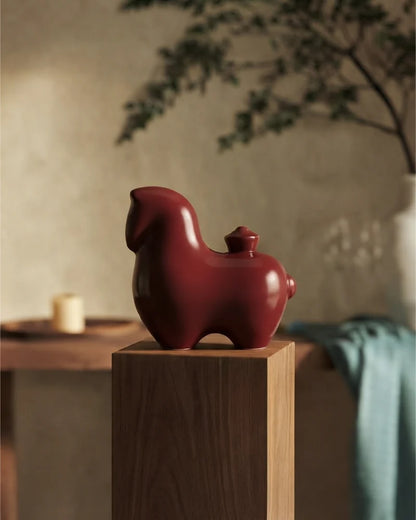 Red Tang horse ceramic figurine displayed on a wooden pedestal in a warm interior