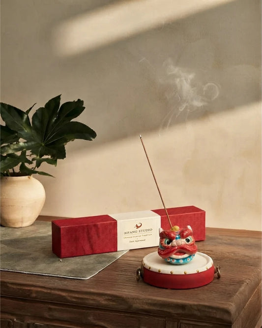 Chinese Guardian Lion incense holder on a drum base beside a red incense box