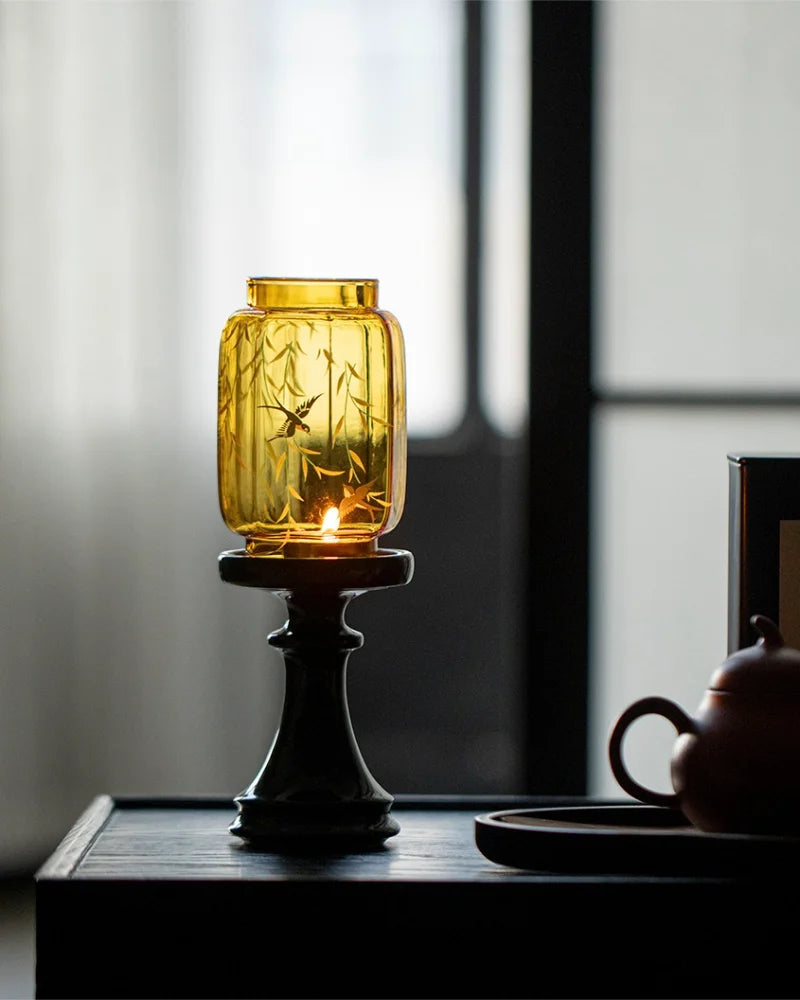 Yellow glass candle lantern with a candle, next to a teapot, shows Chinese fengshui living decoration