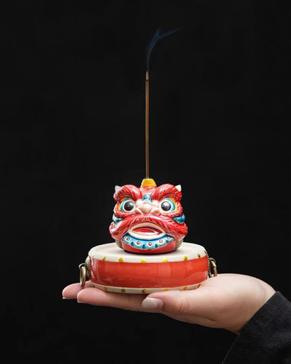 Colorful awaken lion incense holder held in a hand against a black background